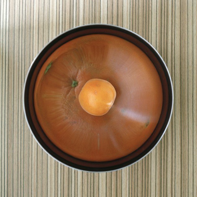 Reflection of an orange in metal bowl, 2010. Pressefoto.